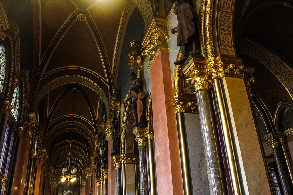 Corredor del Parlamento de Budapest con bóvedas decorativas y estatuas de figuras históricas.