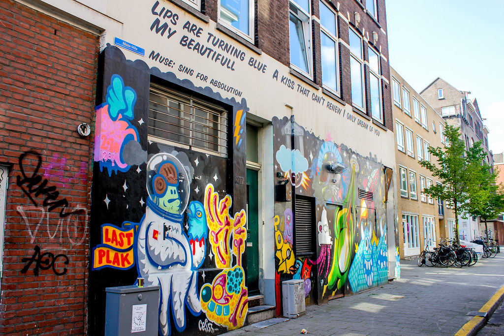 Mural colorido de arte callejero con astronauta y mensajes poéticos en Róterdam.
