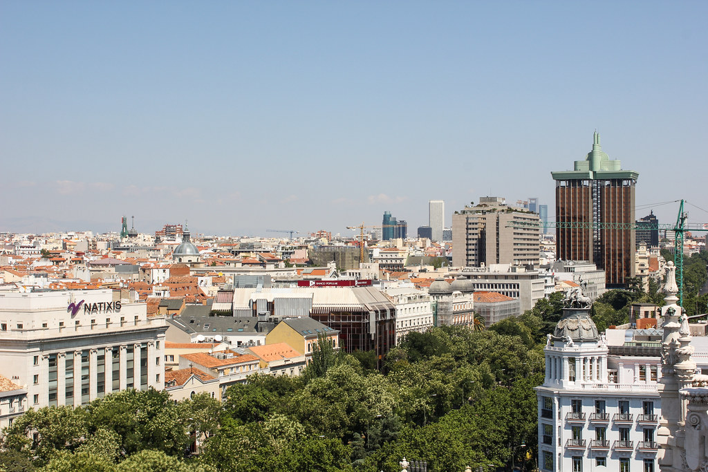 Vista panorámica de la ciudad de Madrid con edificios modernos y tradicionales bajo un cielo azul.