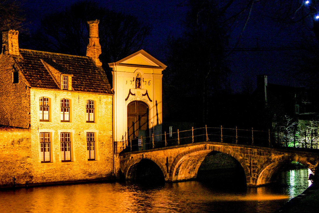 Puente de piedra iluminado de noche en Brujas.