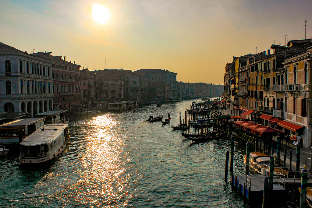 Puesta de sol sobre el Gran Canal de Venecia con góndolas y vaporetto.