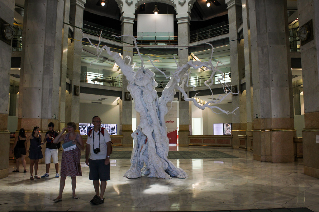Visitantes junto a una escultura moderna en el vestíbulo del Palacio de Comunicaciones en Madrid.